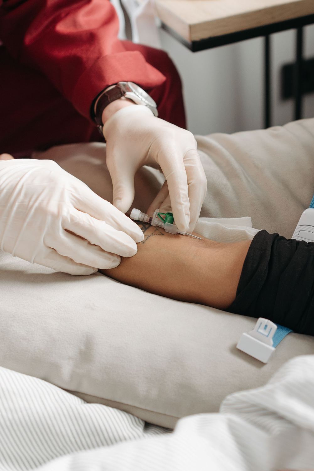 A nurse taking a blood sample at a patient’s bedside, at home.