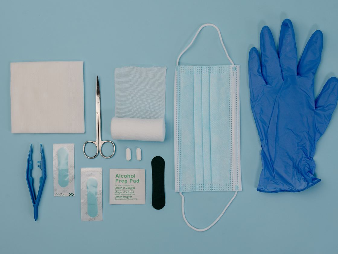 A dressing kit laid out: gauze, scissors, forceps, alcohol prep pads, a mask and gloves.