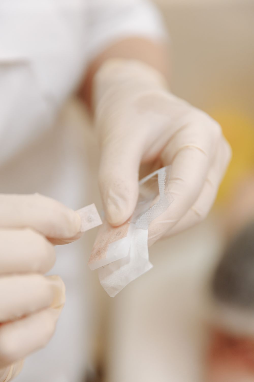 Gloved hands opening a sterile dressing from its sealed packet.