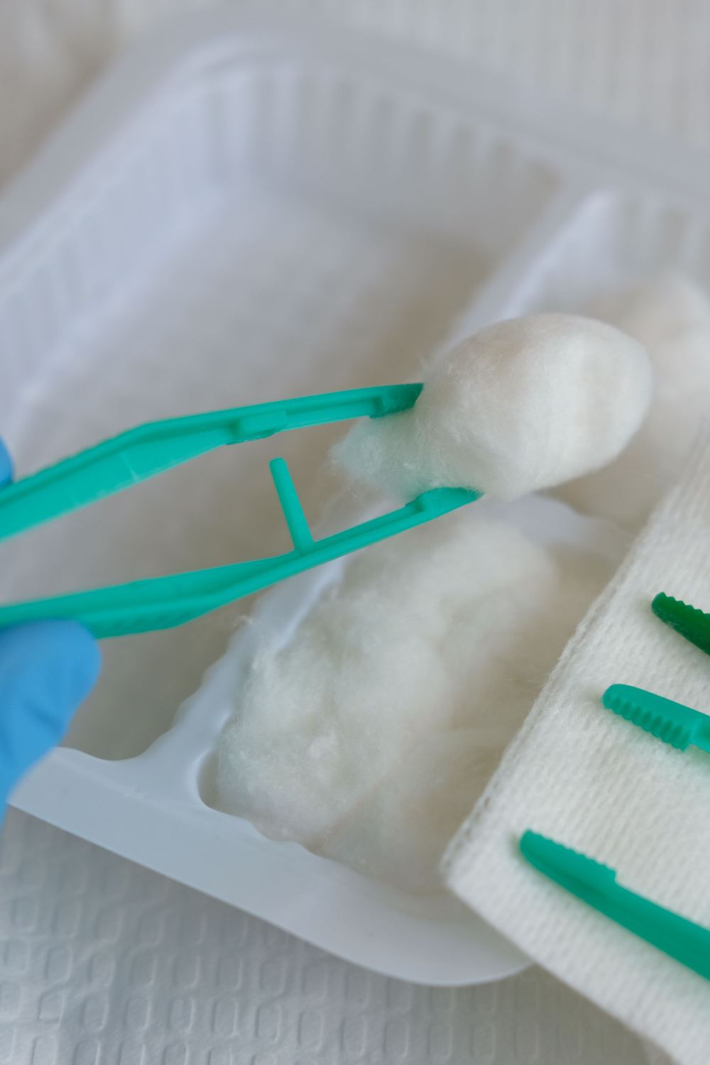 Sterile dressing tray with forceps and cotton balls, ready for a visit.
