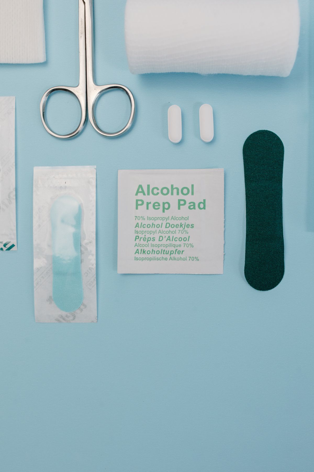 Dressing supplies laid out neatly: gauze, scissors, an alcohol prep pad and a bandage.